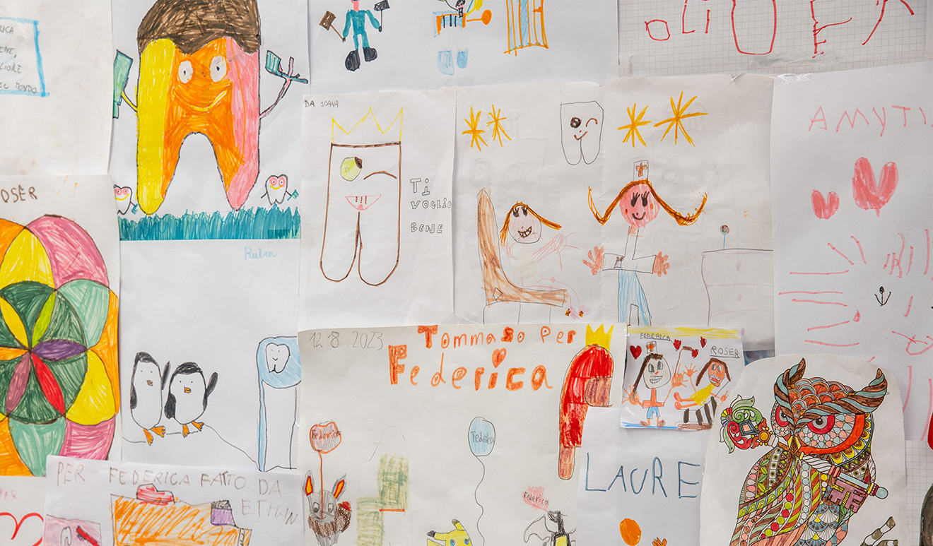 Una parete piena di disegni colorati di bambini che raffigurano denti sorridenti, pinguini e dentisti, celebrando l'odontoiatria pediatrica