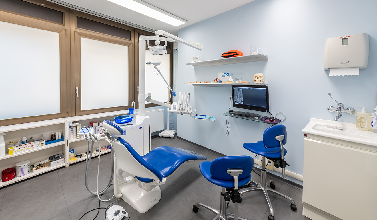 Sala operatoria dello studio dentistico Pellitteri a Bolzano, con poltrona blu, strumentazione moderna e monitor per diagnostica digitale