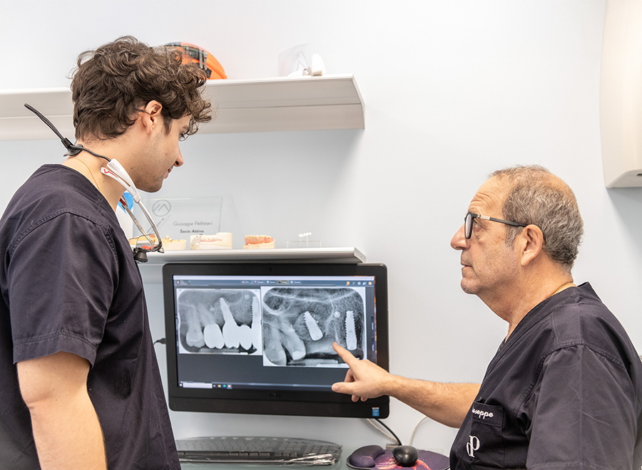 Due odontoiatri dello Studio Pellitteri esaminano radiografie digitali di impianti dentali su un monitor, discutendo un percorso di cura personalizzato