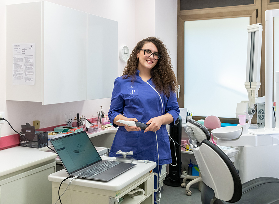 Una dottoressa di Studio Pellitteri sorride e tiene in mano uno scanner intraorale, simbolo delle tecnologie all'avanguardia