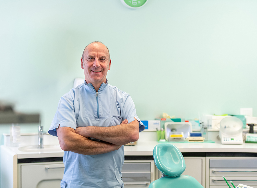 Il Dottor Pellitteri sorride a braccia conserte nel suo moderno studio dentistico a Bolzano