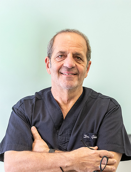 Il Dott. Giuseppe Pellitteri, dentista dello studio di Bolzano, sorride a braccia conserte