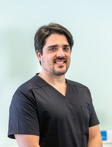 Il Dr. Luca Brucculeri, dentista dello Studio Pellitteri, sorride in primo piano nella sua uniforme