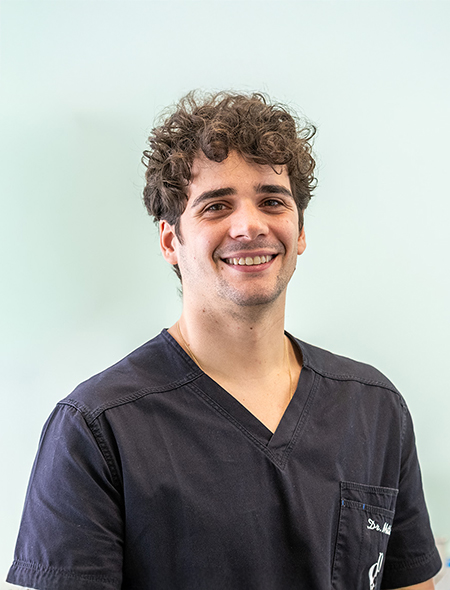 Il Dr. Matteo Pellitteri, dentista del team, sorride in primo piano indossando l'abbigliamento dello studio